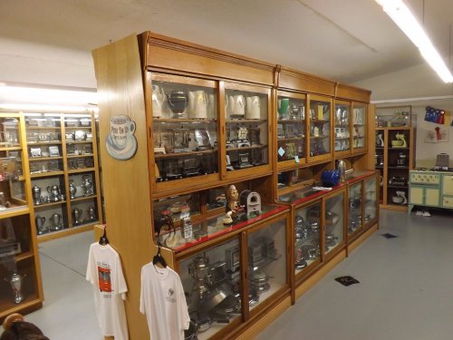 A display of vintage kitchen appliances and utensils in glass cabinets, showcasing a variety of metal and ceramic items.