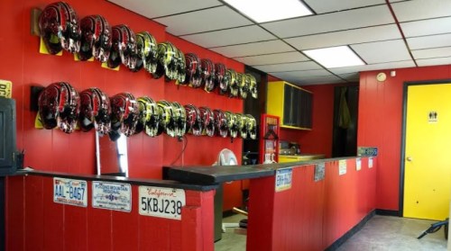 A brightly colored room with red walls, featuring a counter and a display of helmets on the wall.
