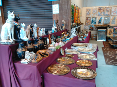 A display of various decorative items, including statues and plates, arranged on tables with a maroon cloth.