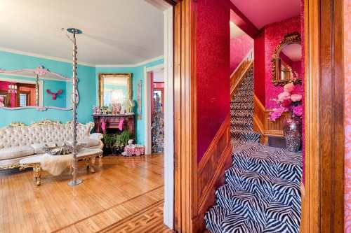 A vibrant interior featuring a pink and blue color scheme, ornate furniture, and a zebra-striped staircase.