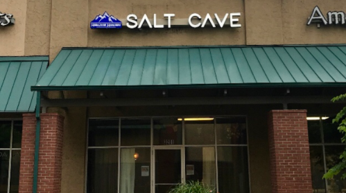 Exterior of a building featuring a sign that reads "SALT CAVE" with a green roof and brick facade.