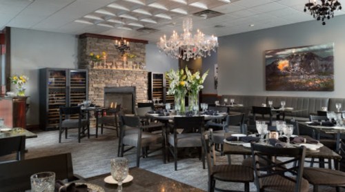 Elegant restaurant interior featuring a stone fireplace, chandelier, and tables set for dining.