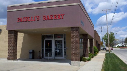 Exterior of Patelli's Bakery, featuring a brick facade and large windows, with a clear blue sky in the background.