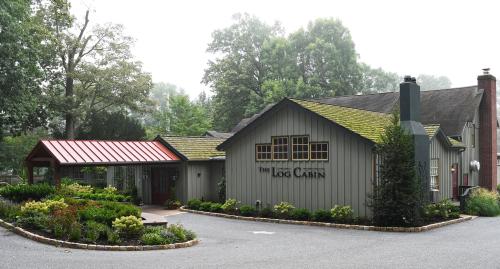 A charming log cabin-style building with a red roof, surrounded by greenery and trees in a misty setting.