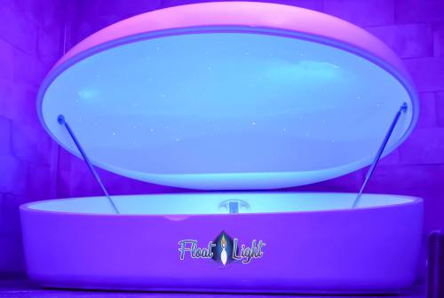 A modern floatation tank with a glowing purple lid, featuring a starry ceiling and the logo "Float Light."