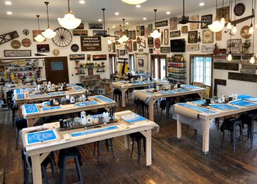 A spacious workshop with wooden tables, tools, and various decorative signs on the walls, ready for creative activities.