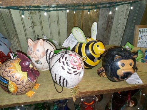 Colorful decorative animal figurines, including a pig, bee, chicken, owl, and bear, displayed on a shelf.