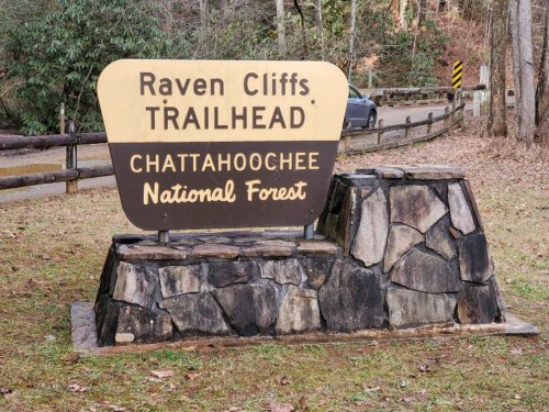 Sign for Raven Cliffs Trailhead in Chattahoochee National Forest, featuring a stone base and surrounded by trees.