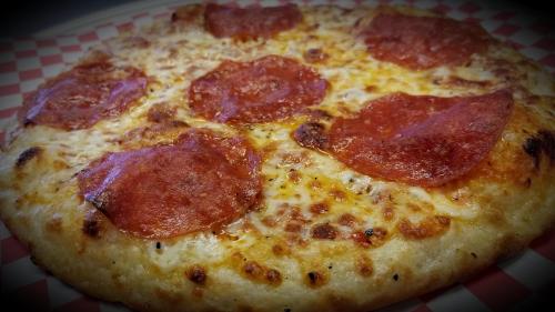A close-up of a pepperoni pizza with melted cheese on a checkered red and white plate.