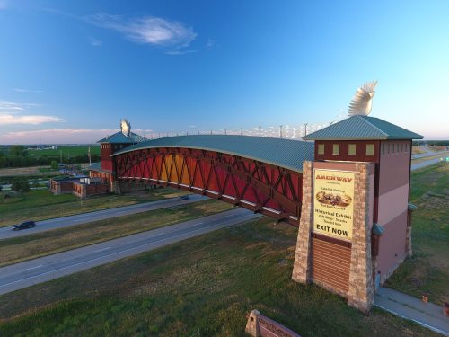 A large, colorful archway structure with a sign for a historical exhibit, set against a clear blue sky.
