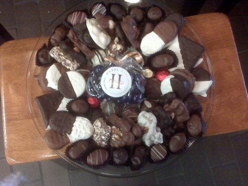 A decorative platter filled with an assortment of chocolates, including truffles, pralines, and chocolate-covered treats.