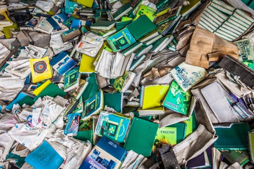 A chaotic pile of scattered, worn books in various colors and sizes, some with torn pages and covers.