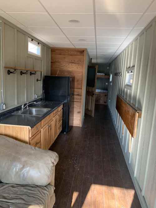 Interior of a narrow, modern cabin featuring a kitchen area, wooden accents, and a cozy living space.