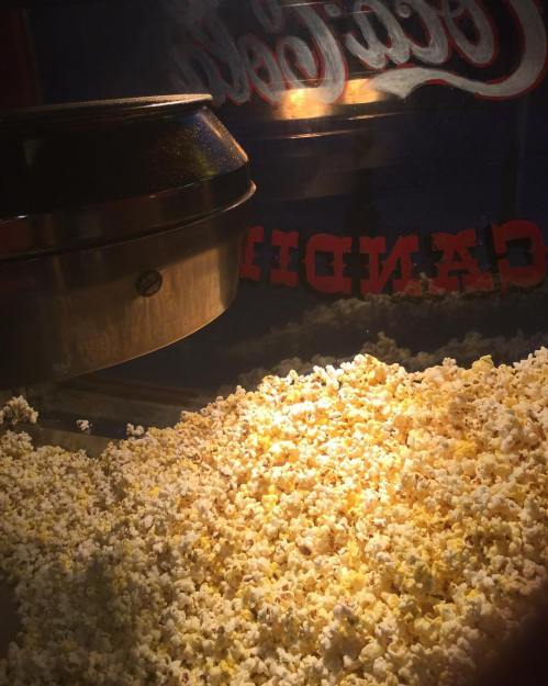 A close-up of freshly popped popcorn in a vintage popcorn machine, illuminated and ready to serve.