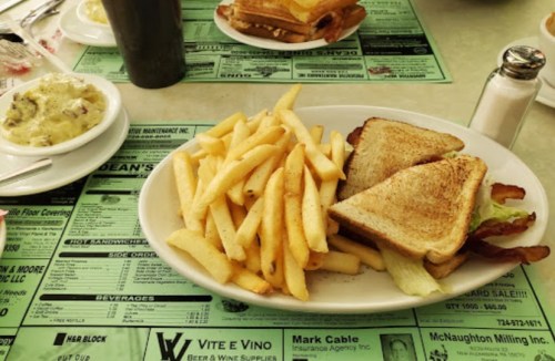 A plate of golden fries and a toasted sandwich on a green menu table.