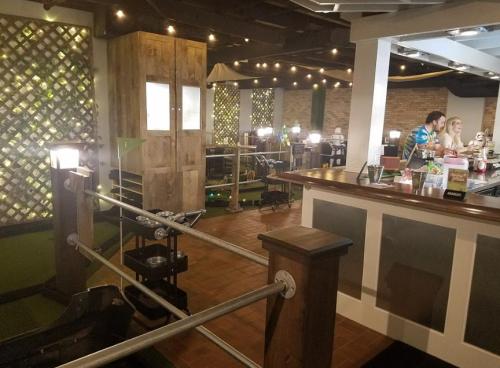 A cozy indoor space with a bar, mini-golf area, and warm lighting, featuring people enjoying drinks and games.