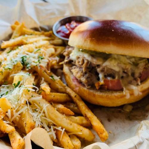 A delicious burger with pulled pork and toppings, served with a side of crispy fries and ketchup.