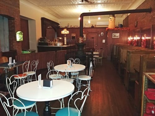 Cozy café interior with white tables, vintage wooden booths, and warm lighting, featuring a rustic charm.