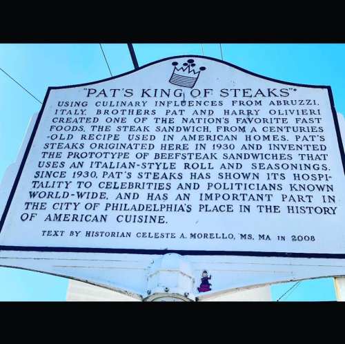 Sign for "Pat's King of Steaks," detailing its history and significance in American cuisine, established in 1930.