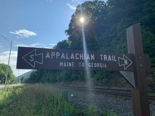 Signpost for the Appalachian Trail, indicating directions to Maine and Georgia, with a sunburst in the background.