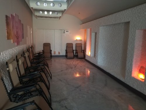 A serene room with reclining chairs, salt lamps, and textured walls, designed for relaxation and wellness.