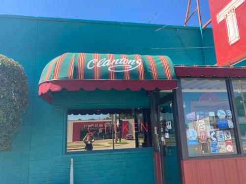 A colorful awning with "Alantons" above a window, featuring a sign that says "CHICKEN" on a bright blue building.