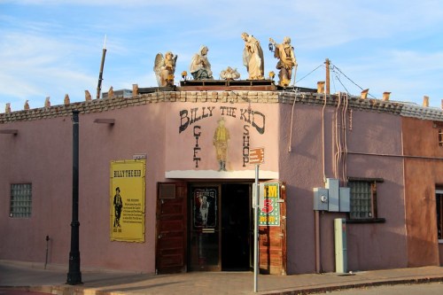 Exterior of the Billy the Kid Gift Shop, featuring statues on the roof and a colorful storefront in a historic style.