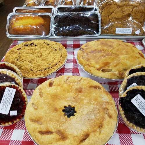 A display of various baked goods, including pies and cakes, on a red and white checkered tablecloth.