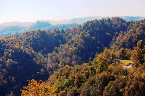 A scenic view of rolling hills covered in autumn foliage under a clear sky.