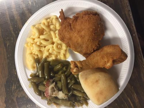A plate of food featuring fried chicken, macaroni and cheese, green beans, and a dinner roll.
