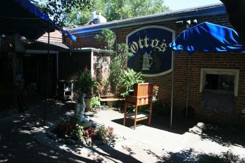 A cozy outdoor seating area with a chair, plants, and a small fountain near a brick building with a sign reading "Otto's."