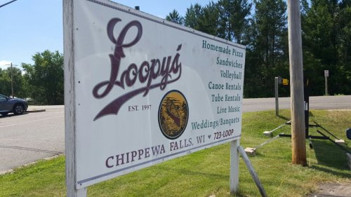 Sign for Loopy's in Chippewa Falls, WI, featuring homemade pizza, sandwiches, volleyball, canoe rentals, and live music.