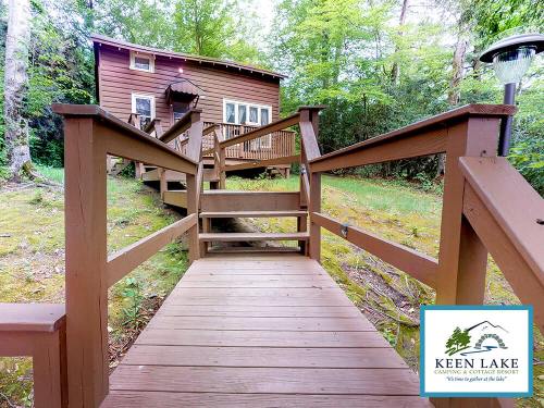 A wooden walkway leads to a cozy cabin surrounded by trees at Keen Lake Camping and Cottage Resort.
