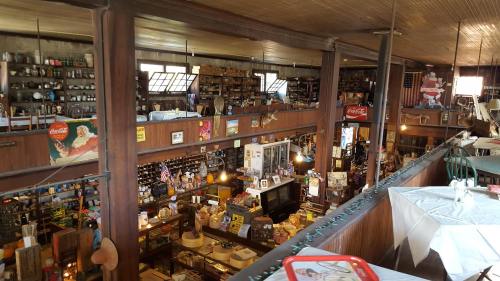 A vintage store interior with wooden beams, shelves filled with various items, and tables set for dining.