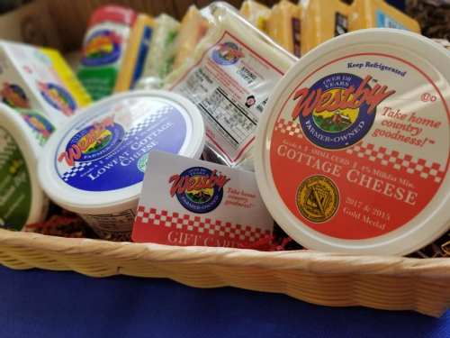 A basket filled with various cheese products and a gift card for Westby Creamery, promoting cottage cheese goodness.
