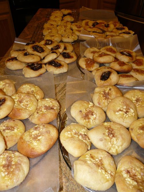 A variety of freshly baked pastries arranged on trays, some topped with nuts and others with fruit fillings.