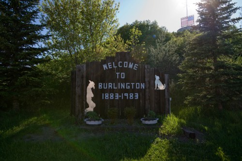 Welcome sign for Burlington, established 1883, with decorative elements and greenery surrounding it.