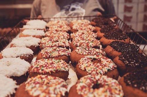 A tray of assorted donuts topped with colorful sprinkles and coconut, arranged in a tempting display.
