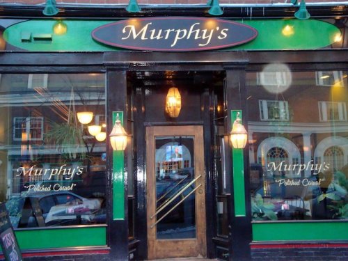 Exterior of Murphy's restaurant, featuring a black and green facade with large windows and decorative lighting.