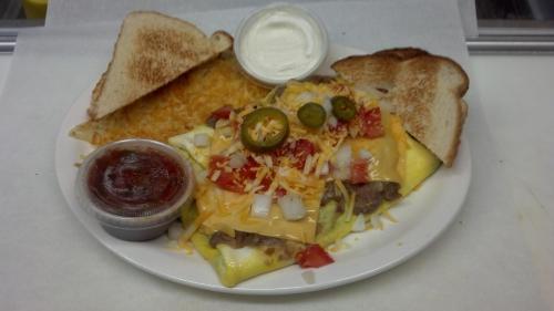 A plate of cheesy omelette topped with jalapeños, onions, and tomatoes, served with toast and salsa on the side.