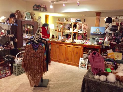 A cozy shop interior featuring handmade clothing, accessories, and decorative items displayed on racks and shelves.