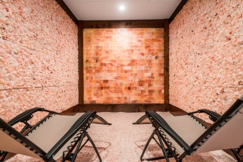 A serene salt room with pink salt walls and two reclining chairs for relaxation.