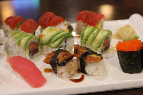 A platter of assorted sushi rolls, including tuna, avocado, and eel, garnished with wasabi and pickled ginger.
