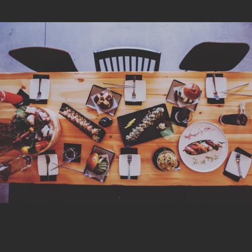A top-down view of a dining table set with various sushi dishes, drinks, and utensils.