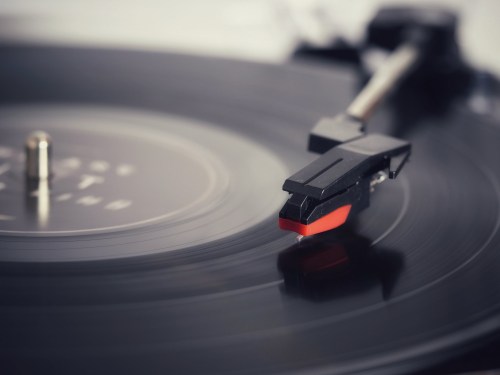 Close-up of a turntable needle resting on a spinning vinyl record, capturing the grooves and motion.