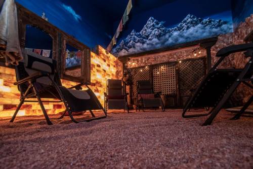 A cozy room with salt brick walls, reclining chairs, and a mountain mural, illuminated by soft lights.
