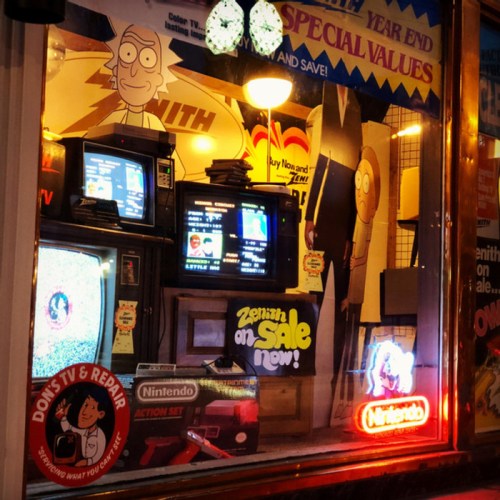 A retro store window displays vintage TVs, a Nintendo sign, and cartoon characters, creating a nostalgic atmosphere.