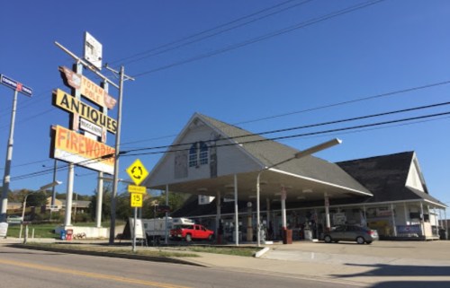 A vintage building with a large sign advertising antiques and fireworks, set against a clear blue sky.