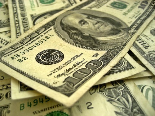 Close-up of scattered U.S. hundred-dollar bills on a surface.