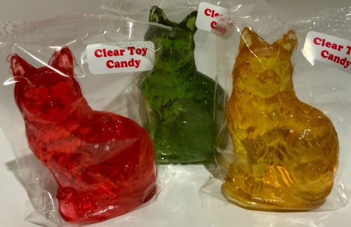 Three colorful, transparent cat-shaped candies in red, green, and yellow, packaged in clear plastic.